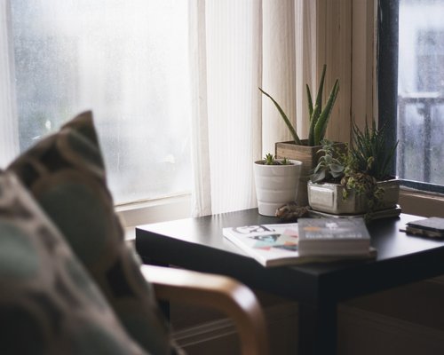 Person arranging their home office desk near a window to catch side lighting